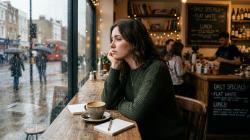 Woman reflecting thoughtfully at a cafe window
