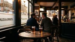 Quiet British pub at golden hour with two pint glasses on a table by a frosted bar window, an evocative scene for adult sex meets in the UK.
